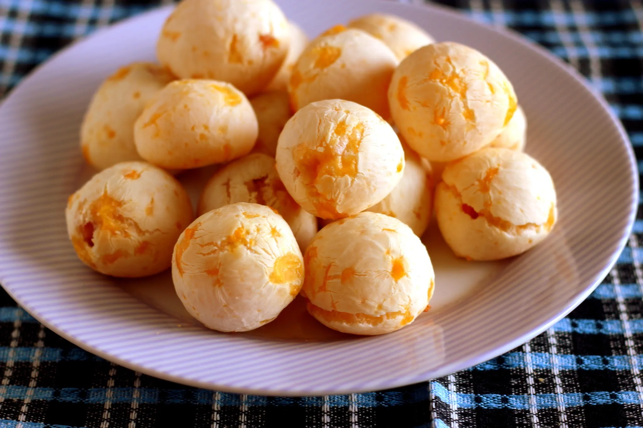 Pães de queijo dispostos em uma mesa com café.